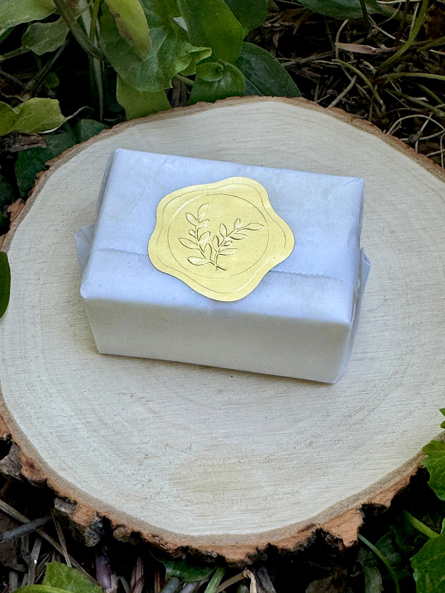 A small package of 6 scented soy wax melts approximately the size of a quarter wrapped in white wax paper and sealed with a small gold seal.